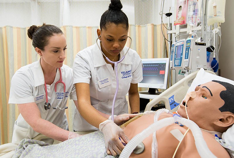 Two nursing students examine patient mannequin in simulation center